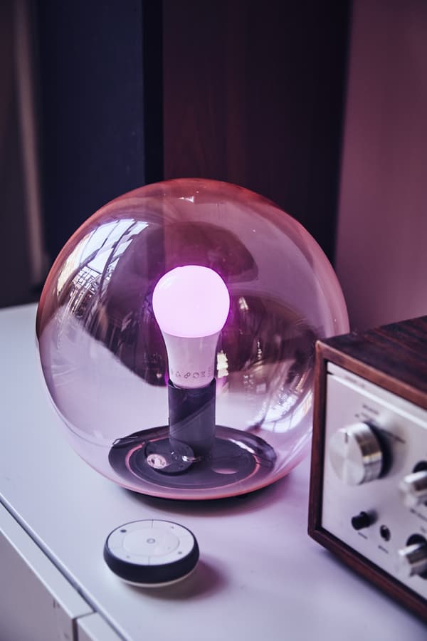 A round, see-through pink glass table lamp with a remote.