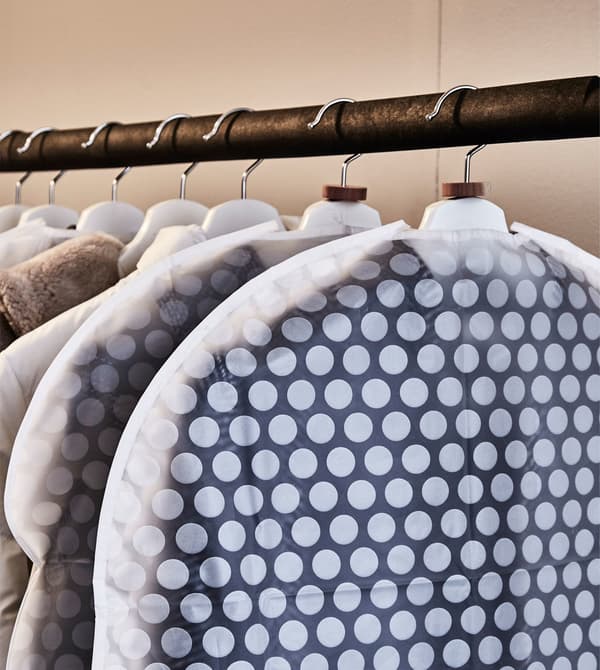 A roupa almacénase en bolsas para a roupa e pendúrase dunha barra nun faiado.