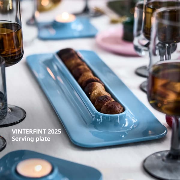 A row of meatballs is on a blue VINTERFINT serving plate, on a festively decorated table.