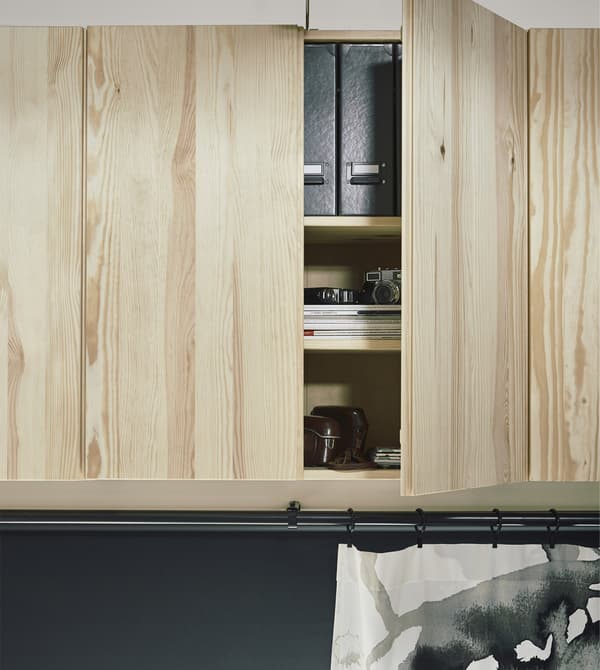 A row of natural wood IVAR cabinets mounted up high for extra storage in a loft apartment.