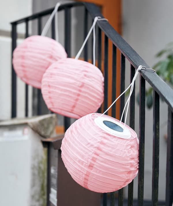 A row of SOLVINDEN lamps hung along the handrail of a short staircase leading up to the entrance of a building.