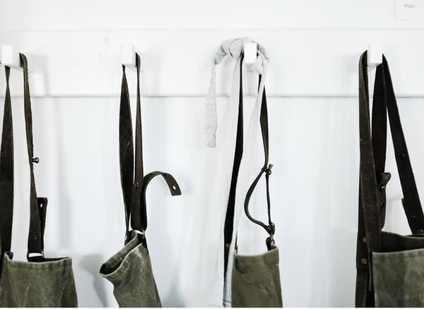 A row of white hooks that are holding Annika’s aprons for her pottery studio.