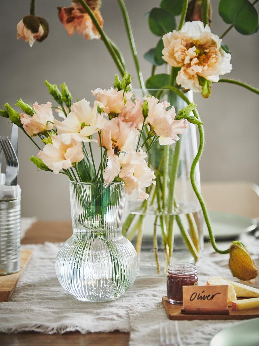 A rustic centrepeice can be seen with cut flowers in a clear glass vase.  