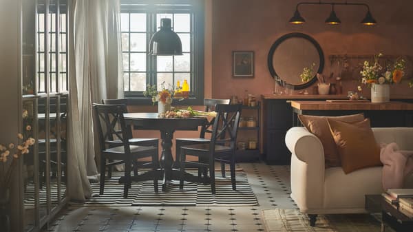 A rustic dining, kitchen and living space with apricot-coloured walls, an INGATORP extendable table and four INGOLF chairs.