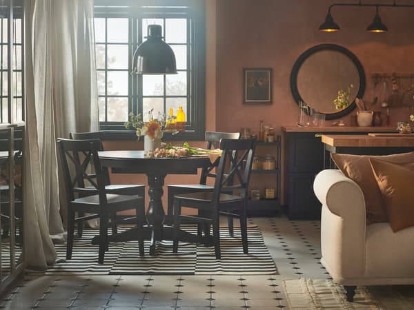 A rustic dining, kitchen and living space with apricot-coloured walls, an INGATORP extendable table and four INGOLF chairs.