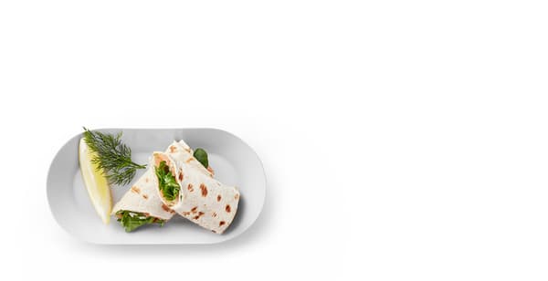 A sample portion of salmon wrap with a sprig of dill and a slice of lemon.