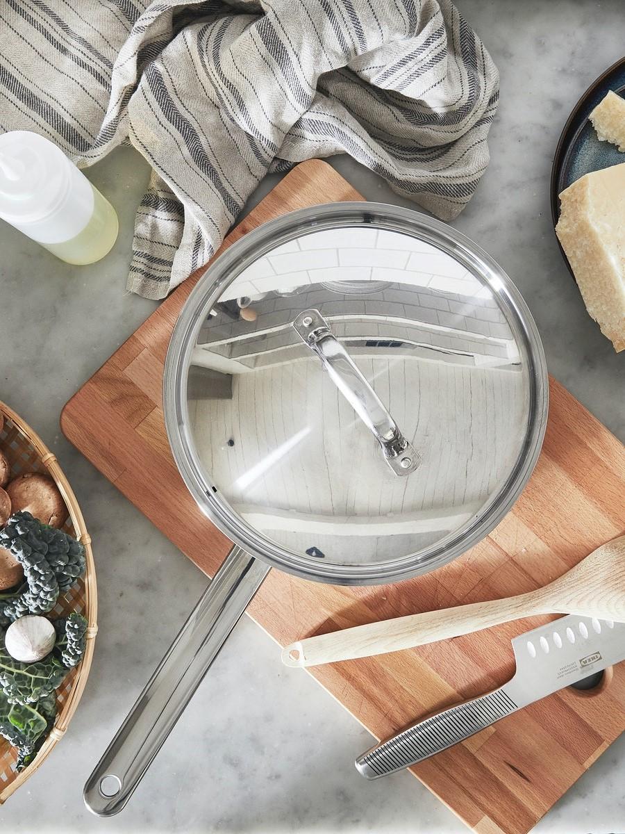 A sauté pan with meatballs and sauce inside stands on a black induction hob.