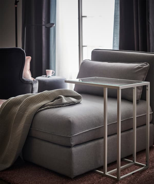 A seating module in grey with a nearby laptop stand.