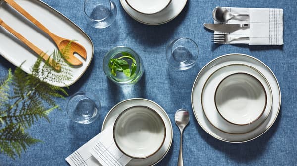 A section of a decorated table with gray GLADELIG plates and bowls, set on a dark-blue SEVÄRD tablecloth.