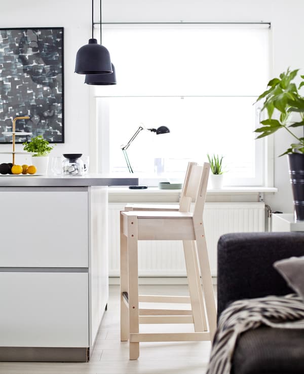 A section of white kitchen island with a pale-wood stool.