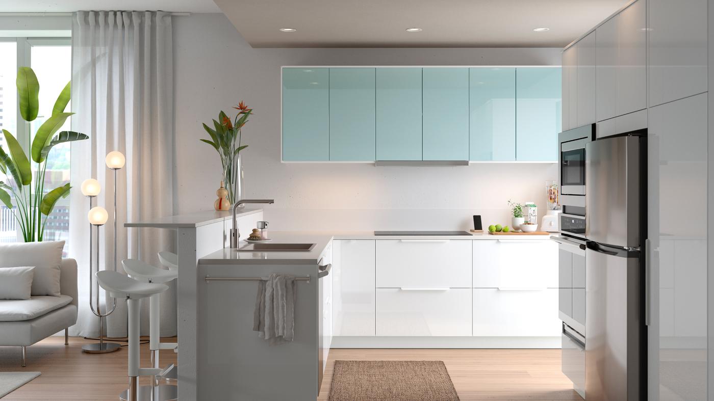 A SEKTION kitchen in white with a sink, a sofa, and on the wall are cabinets with JÄRSTA kitchen fronts in light turquoise.