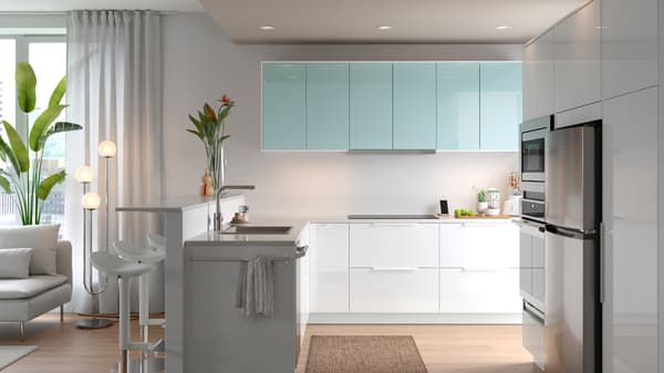 A SEKTION kitchen in white with a sink, a sofa, and on the wall are cabinets with JÄRSTA kitchen fronts in light turquoise.