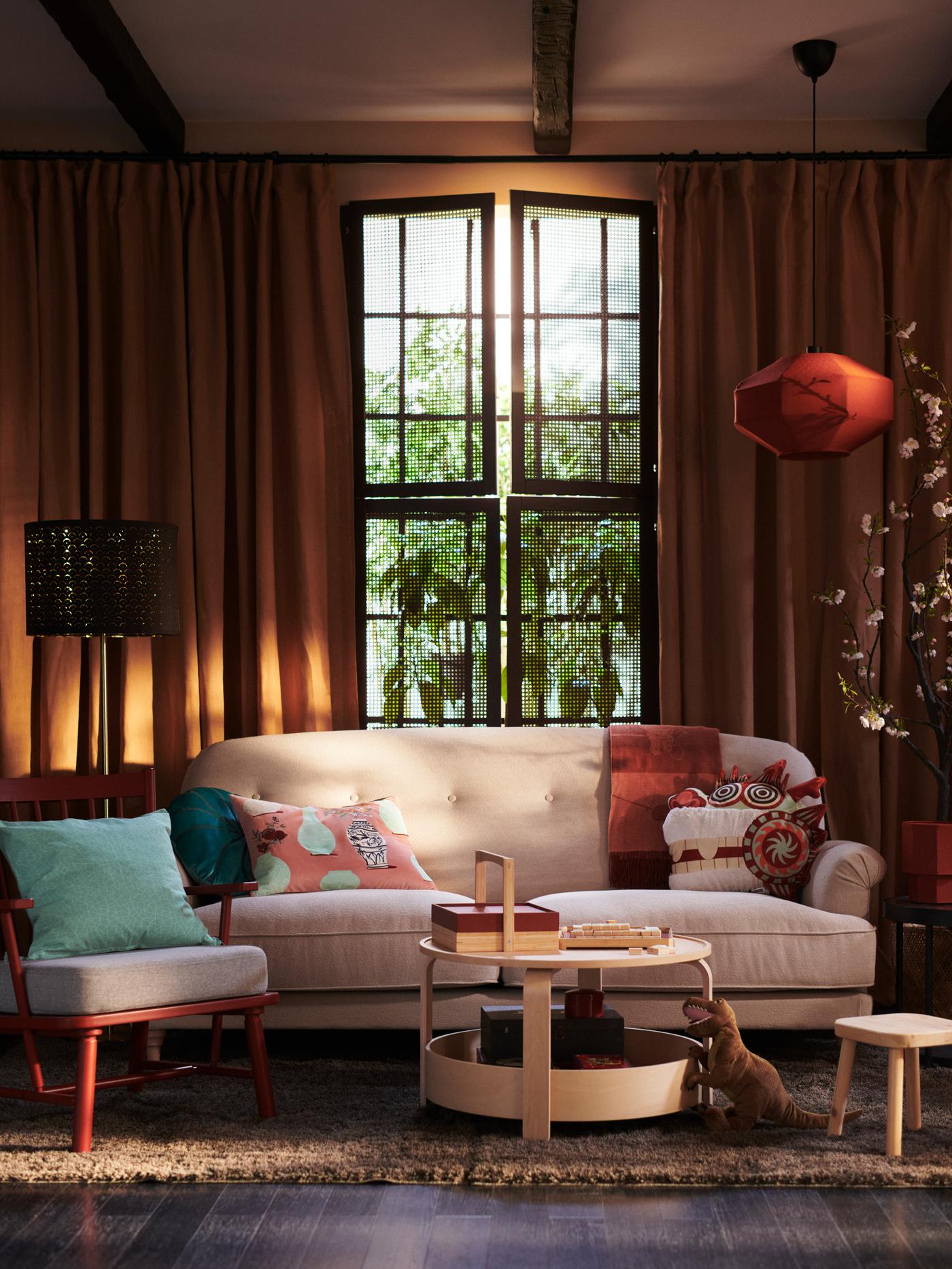 A selection of cushions in FÖSSTA cushion covers arranged on a sofa and armchair, with a FÖSSTA lampshade in the background.