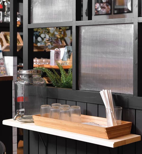 A self-service area featuring drinking glasses and a glass water dispenser.