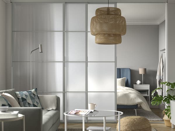 A semitransparent SKYTTA sliding door dividing a livingroom from the bedroom.