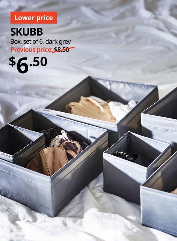 A set of grey SKUBB boxes spread open on a white bedsheet to show neatly organised clothing items in other SKUBB boxes. 