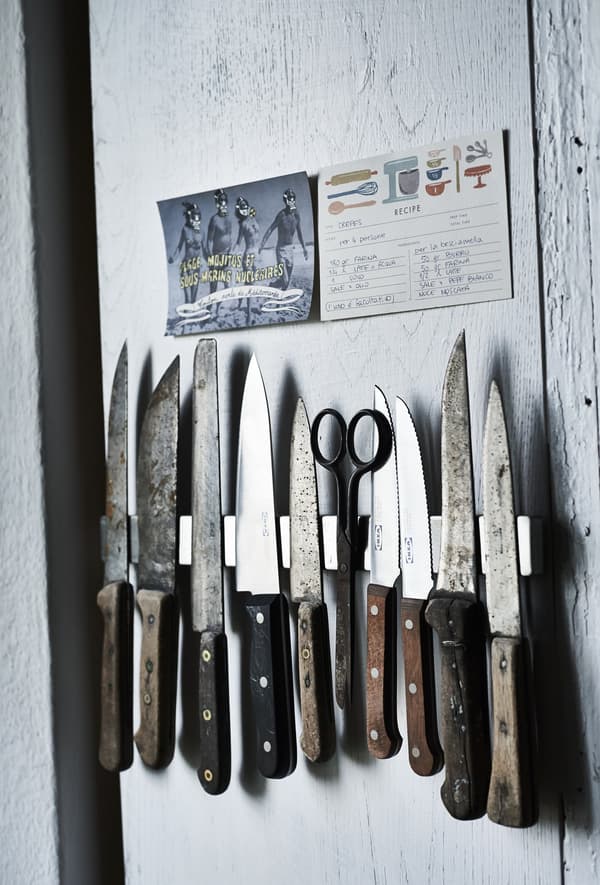 A set of vintage knives fixed to a kitchen wall.
