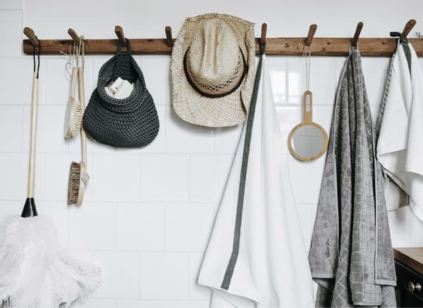 A set of wooden hooks mounted on a white wall to make bathroom essentials easy to reach.