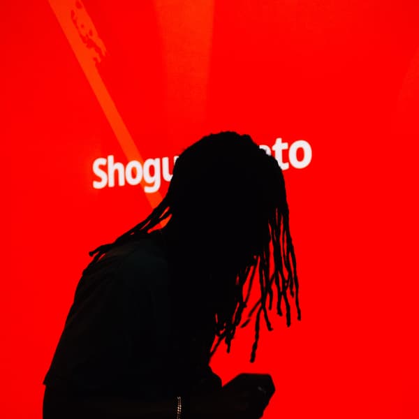 A shadow of a man in front of a red screen with white text.