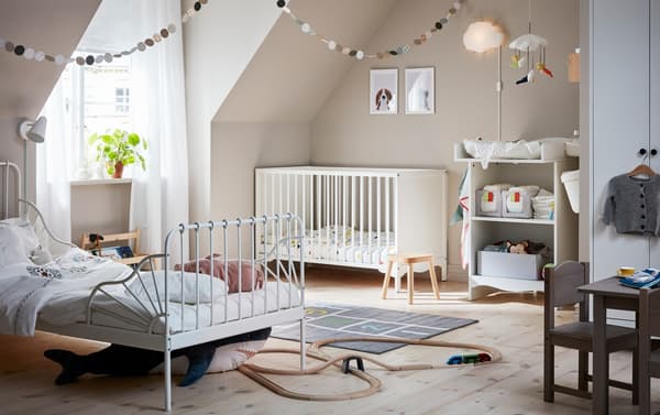 A shared children’s bedroom with white SOLGUL cot and changing table and MINNEN extendable bed.