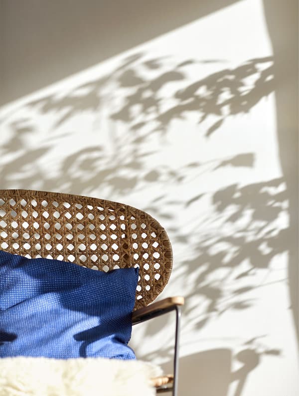 A sheepskin and blue cushion on a wicker rocking chair.
