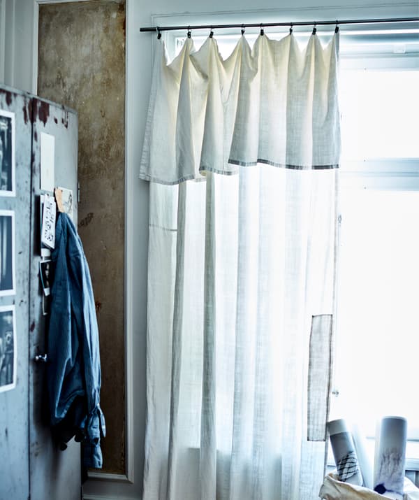 A sheer curtain hangs across a window next to a metal cabinet.