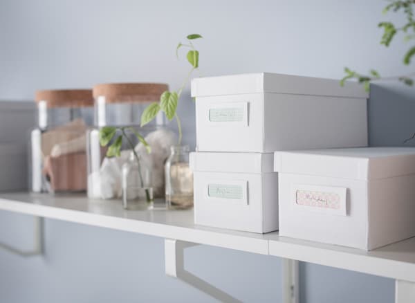 A shelf in white and light wood with boxes and jars for storage.