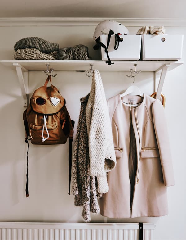 A shelf with boxes on top and hooks underneath.