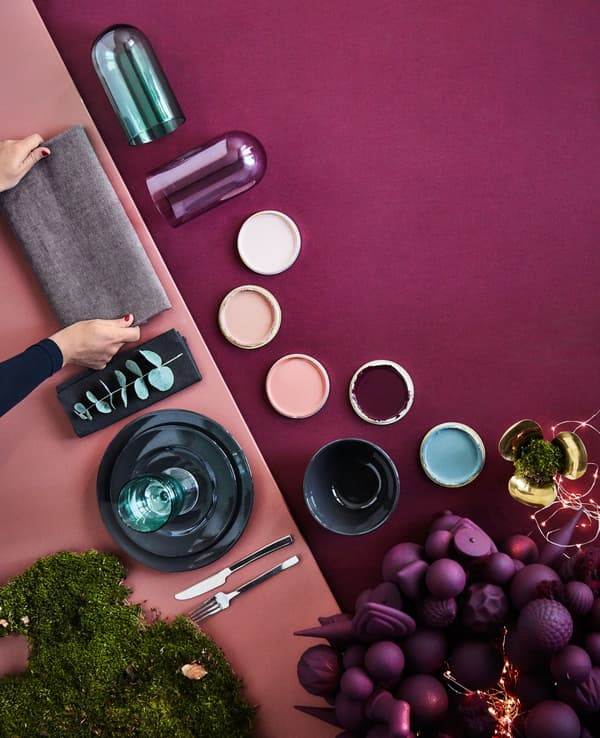 A shot from above of a table being set in a graphic manner in dark red and green tones.