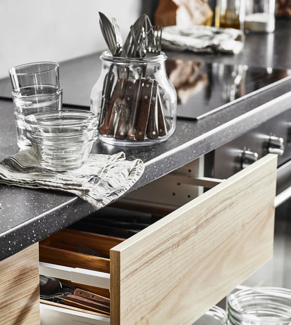 A side view of an open, ash effect drawer with a cutlery tray