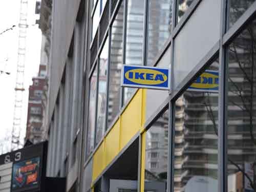A sign reading “IKEA” in classic brand colors hangs on the side of a building in New York.