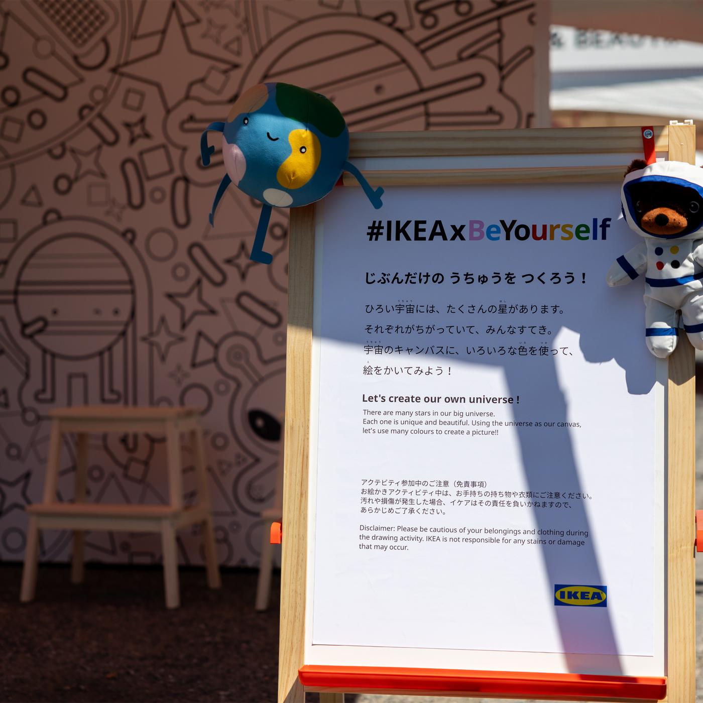 A sign with stuffed animals hanging from it, with the hashtag #IKEAxBeYourself written on it.