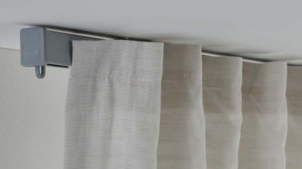 A silver VIDGA 1-track curtain track is mounted on a white ceiling. There's a curtain on it.