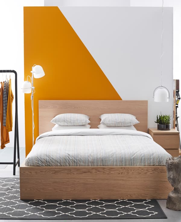A simple, clean bedroom with a graphic orange and white accent wall.
