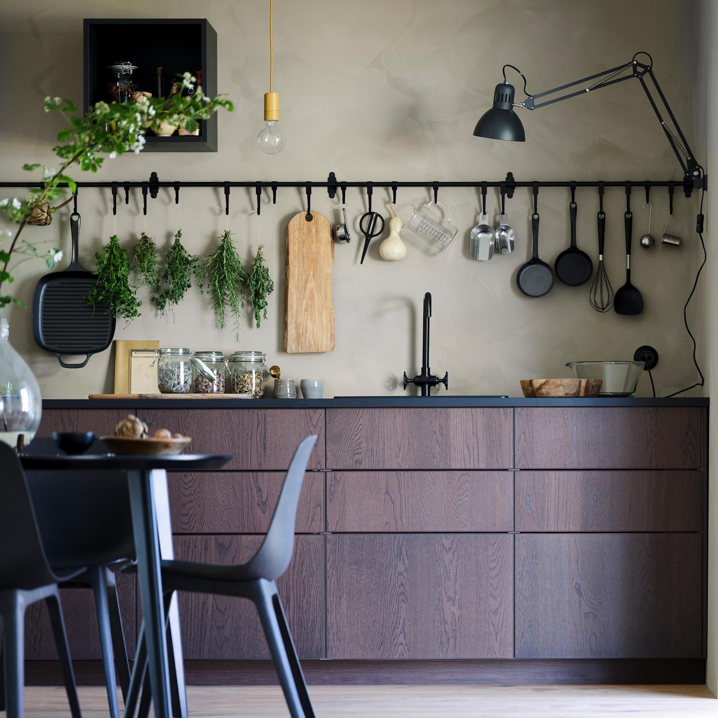 A SINARP kitchen with a table and chairs, and a HULTARP rail and hook hanging on the wall.