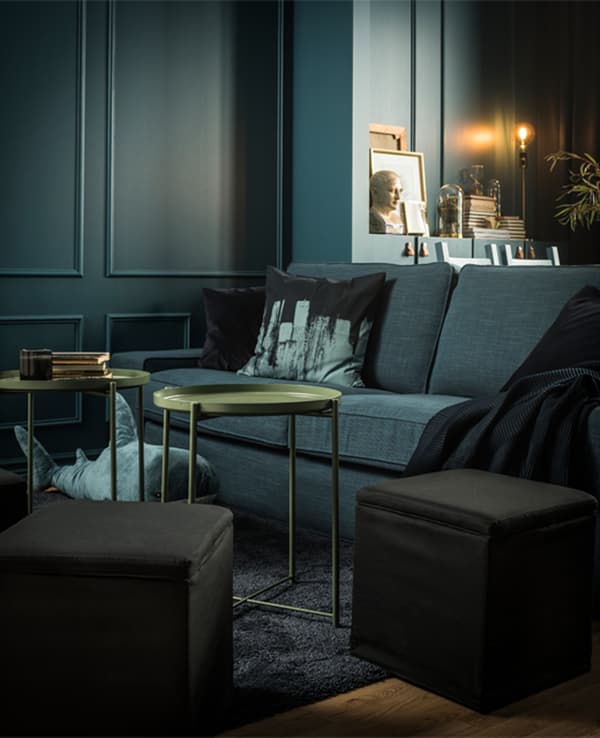 A sitting area is decorated with a sofa, textiles, ottomans, and two small tables.