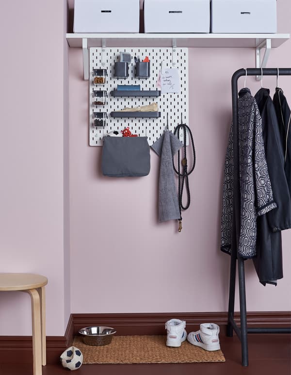 A SKÅDIS pegboard connected to a shelf in a hallway with accessories to hold dog-related stuff like toys, leashes, treats and brushes