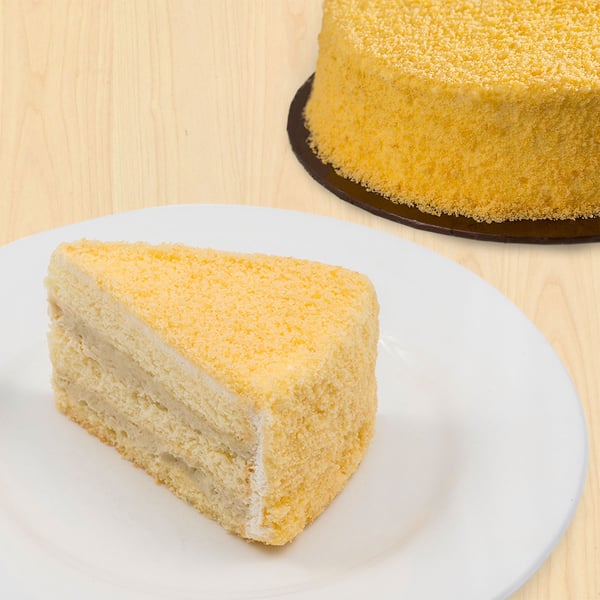 A slice of durian cake and a round durian cake in the background.