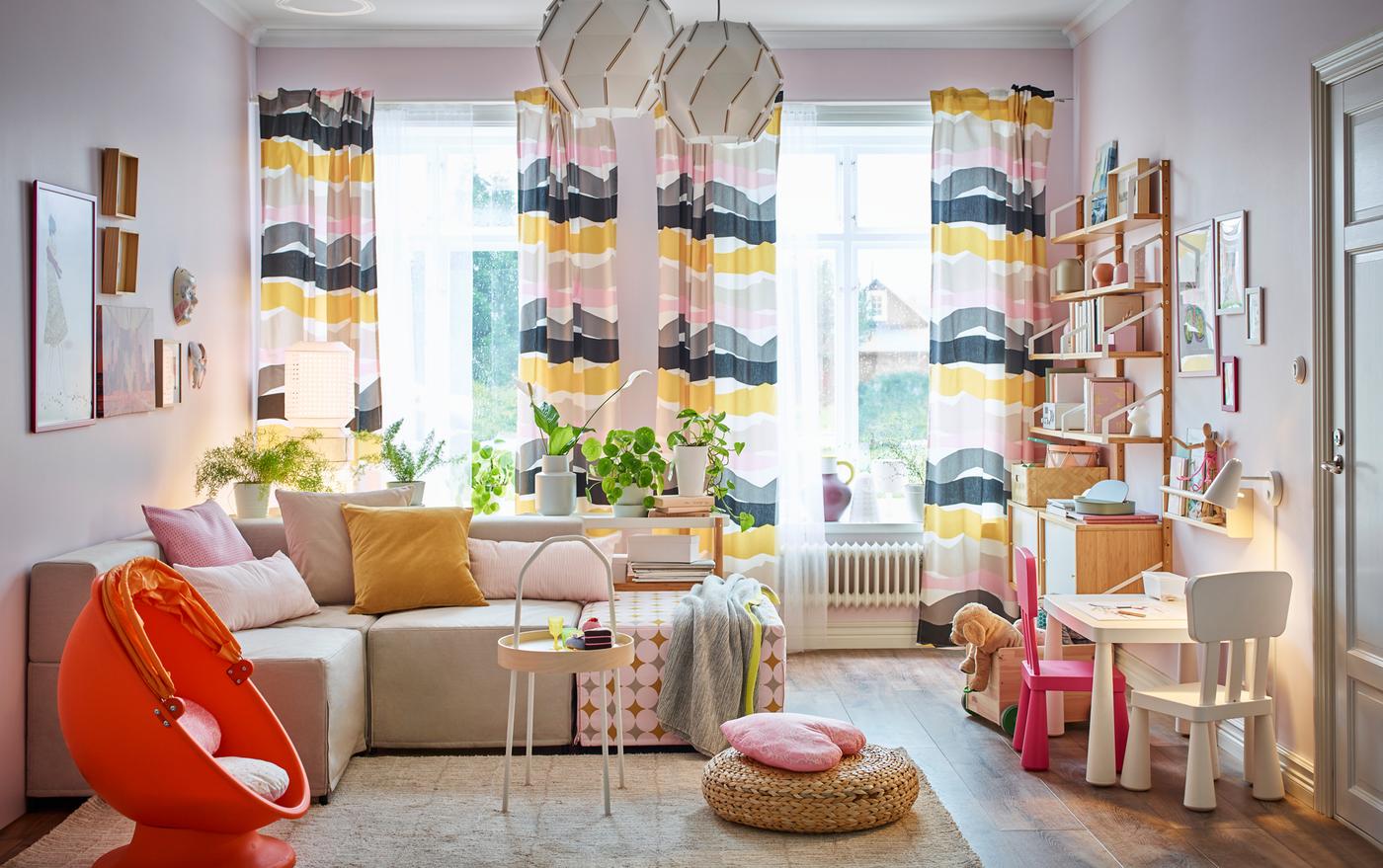 A small, beige, pink and yellow, family living room with the modular KUNGSHAMN 4-seat sofa in beige and multicolour in the centre. 