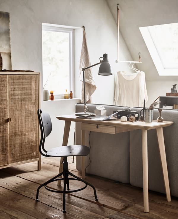A small desk is placed directly behind a sofa bed.