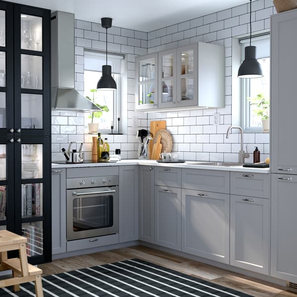 A small grey and white, traditional style kitchen with LERHYTTAN grey and black stained glass doors.