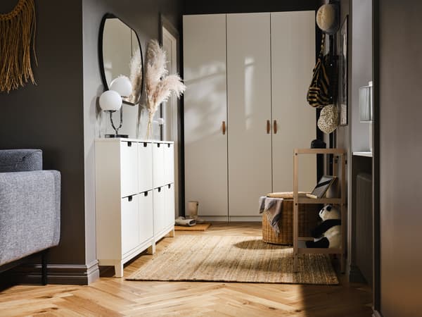 A small hallway with a PAX/FORSAND wardrobe at one end and two white STÄLL shoe cabinets with 4 compartments on one side.
