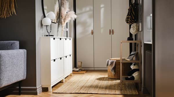 A small hallway with a PAX/FORSAND wardrobe at one end and two white STÄLL shoe cabinets with 4 compartments on one side.