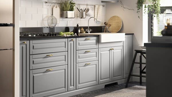 A small kitchen with grey kitchen cabinets, a black mineral-effect worktop, a white sink with a visible front and a gas hob.