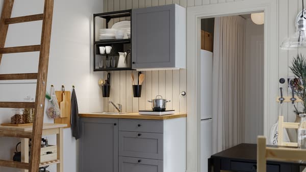 A small kitchen with open shelves in anthracite, grey fronts, a wood worktop, a black table and two wooden chairs.