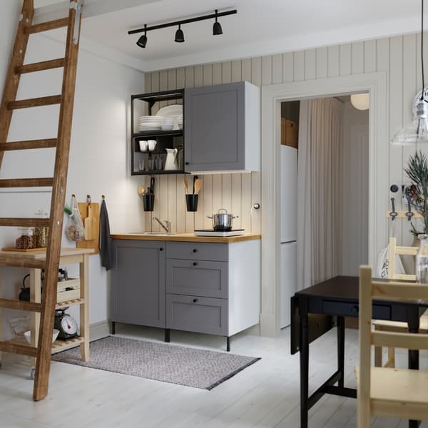 A small kitchen with open shelves in anthracite, grey fronts, a wood worktop, a black table and two wooden chairs.