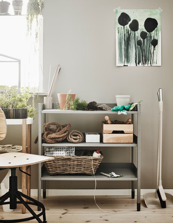 A small metal shelf that serves as a planting station sits in the corner of a room.