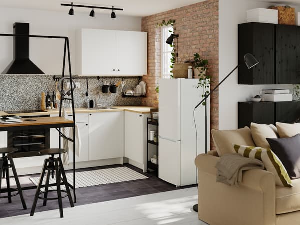 A small open-plan kitchen fitted with modules from the KNOXHULT series. A HÅVERUD table with storage ladder is on one side.
