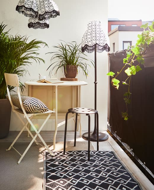 A small sitting area with a table and two chairs gains privacy from a black wind shield.