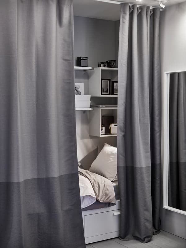 A small sleeping area behind partially-drawn dark grey curtains used to create privacy.